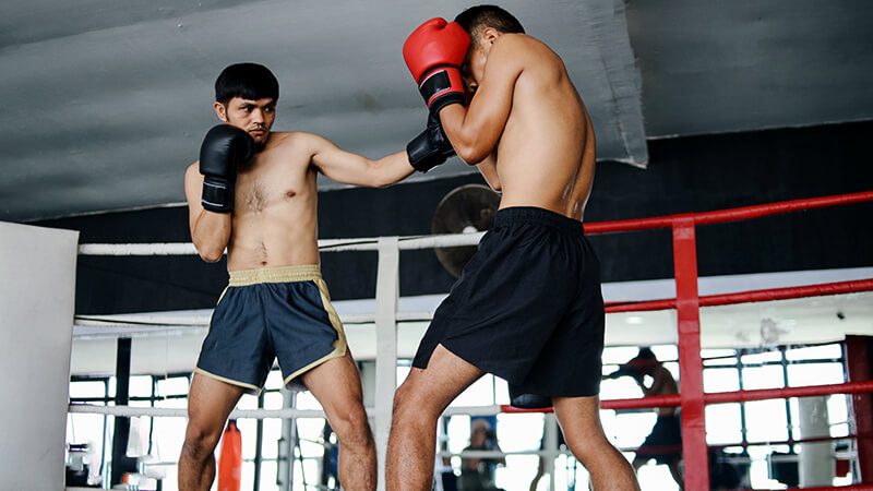 Praticantes de Muay Thai demonstrando postura de combate no ringue.